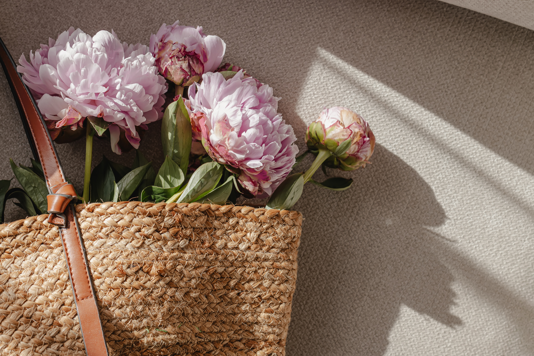 Pink peonies in the straw bag, summer lifestyle